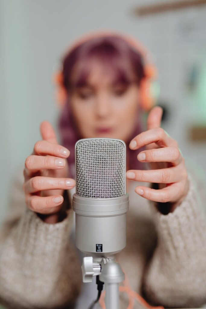 Close-up of a woman recording ASMR with a microphone indoors.